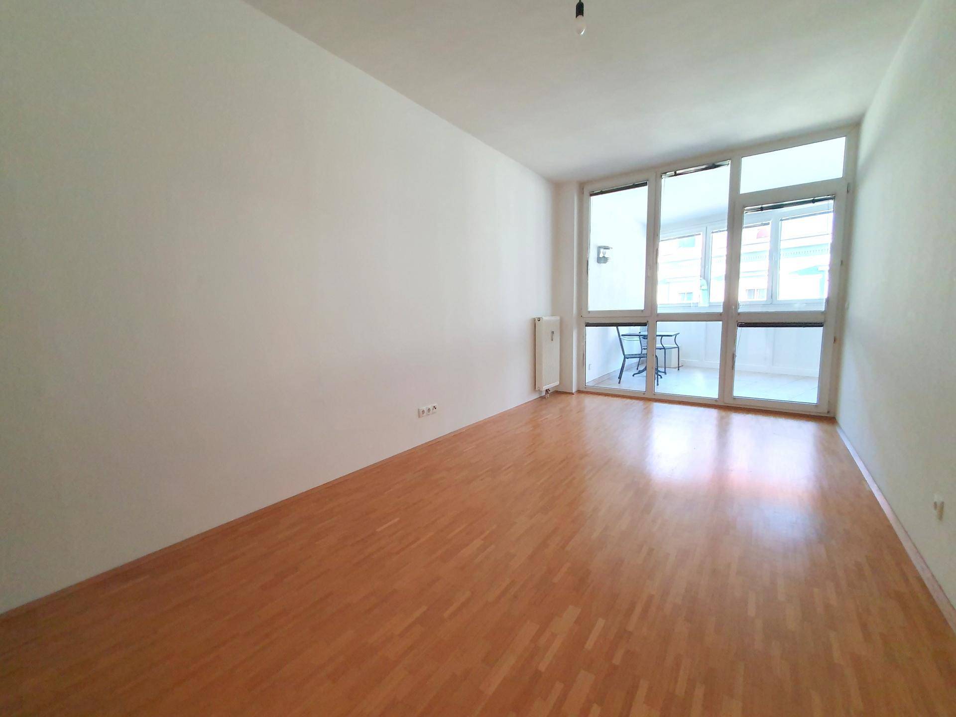 Helles Zimmer mit Parkettboden und großen Fenstern, bietet vielseitige Nutzungsmöglichkeiten.