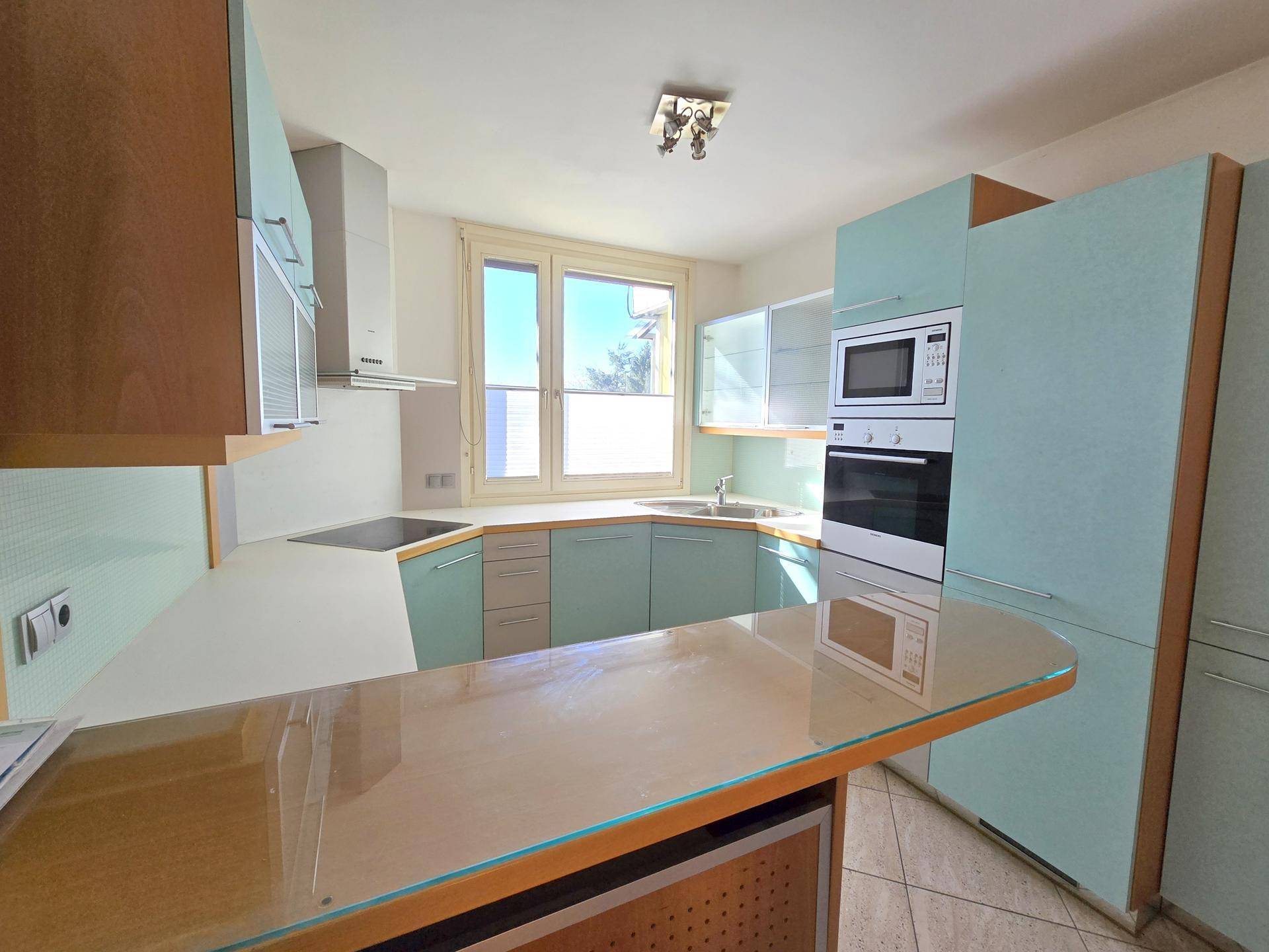 Funktionale Küche mit hellblauen Schränken, Einbaugeräten und Fenster für Tageslicht.