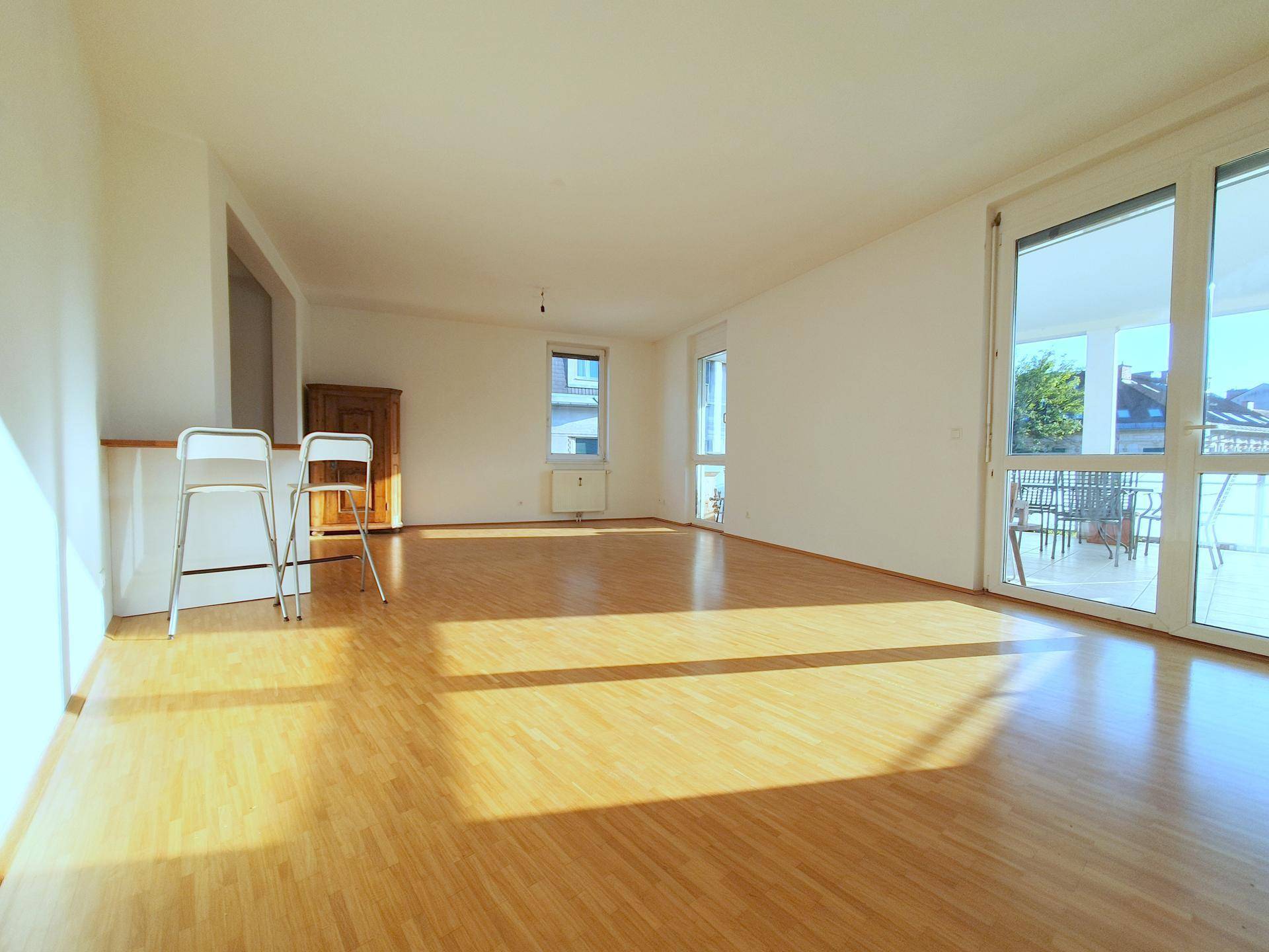 Helles und geräumiges Wohnzimmer mit Parkettboden und Zugang zur Terrasse.