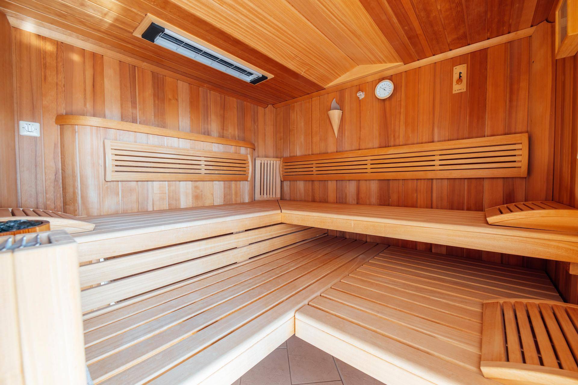 Traditionelle Holzsauna mit mehreren Bänken und einem Heizofen, ideal zur Entspannung.