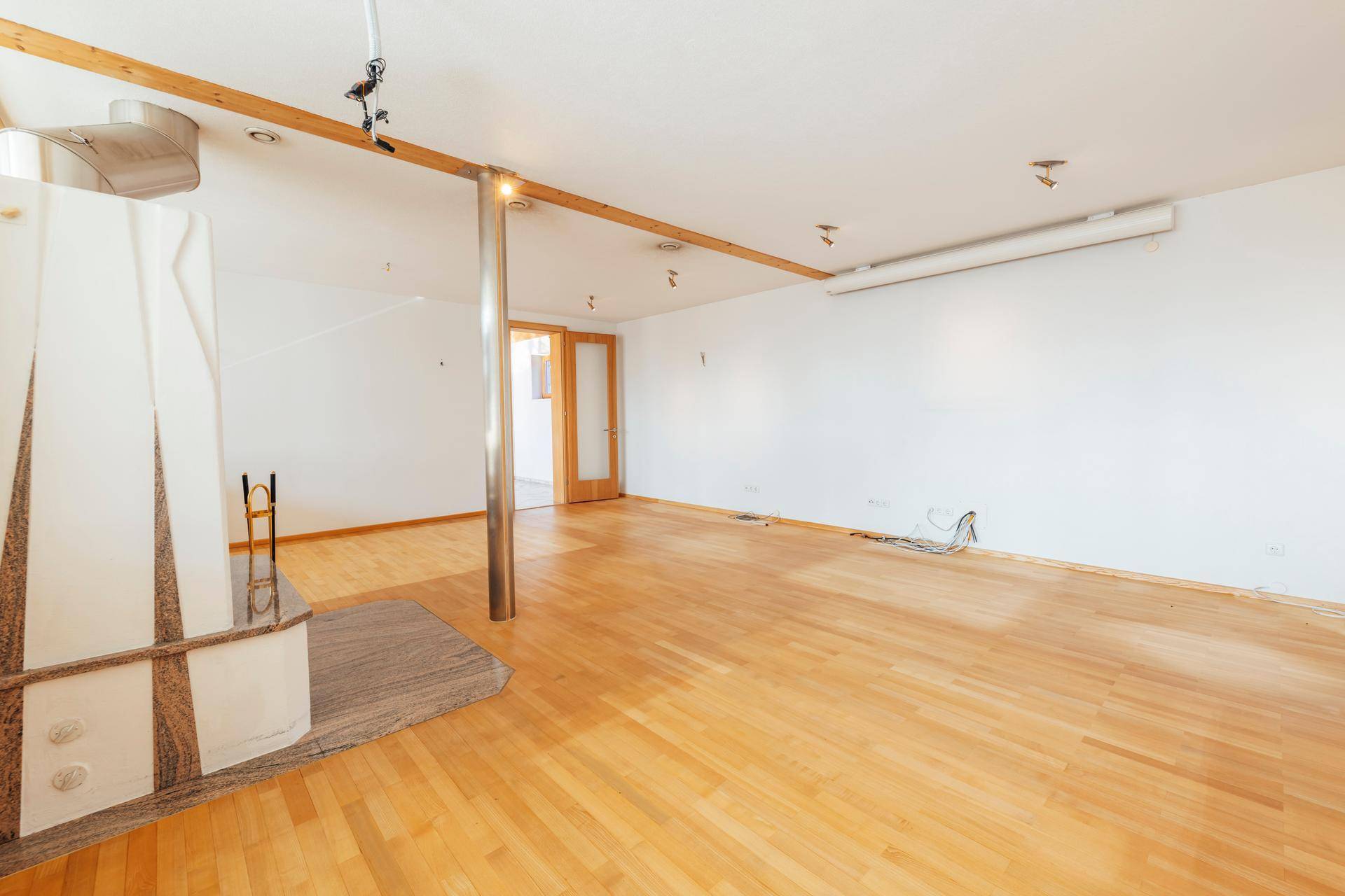 Helles Wohnzimmer mit Holzboden, Kamin und viel Tageslicht, bereit für individuelle Gestaltung.