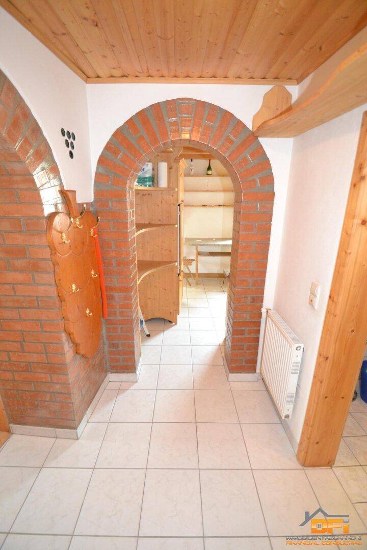 Flur mit Ziegelbogen, Fliesenboden und Holzdetails, der zu einem weiteren Raum führt.