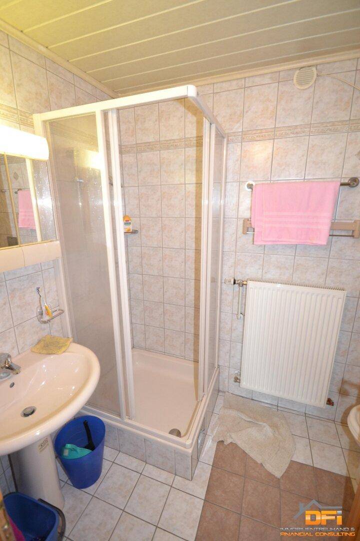 Helles Badezimmer mit Duschkabine, Standwaschbecken und gefliesten Wänden.