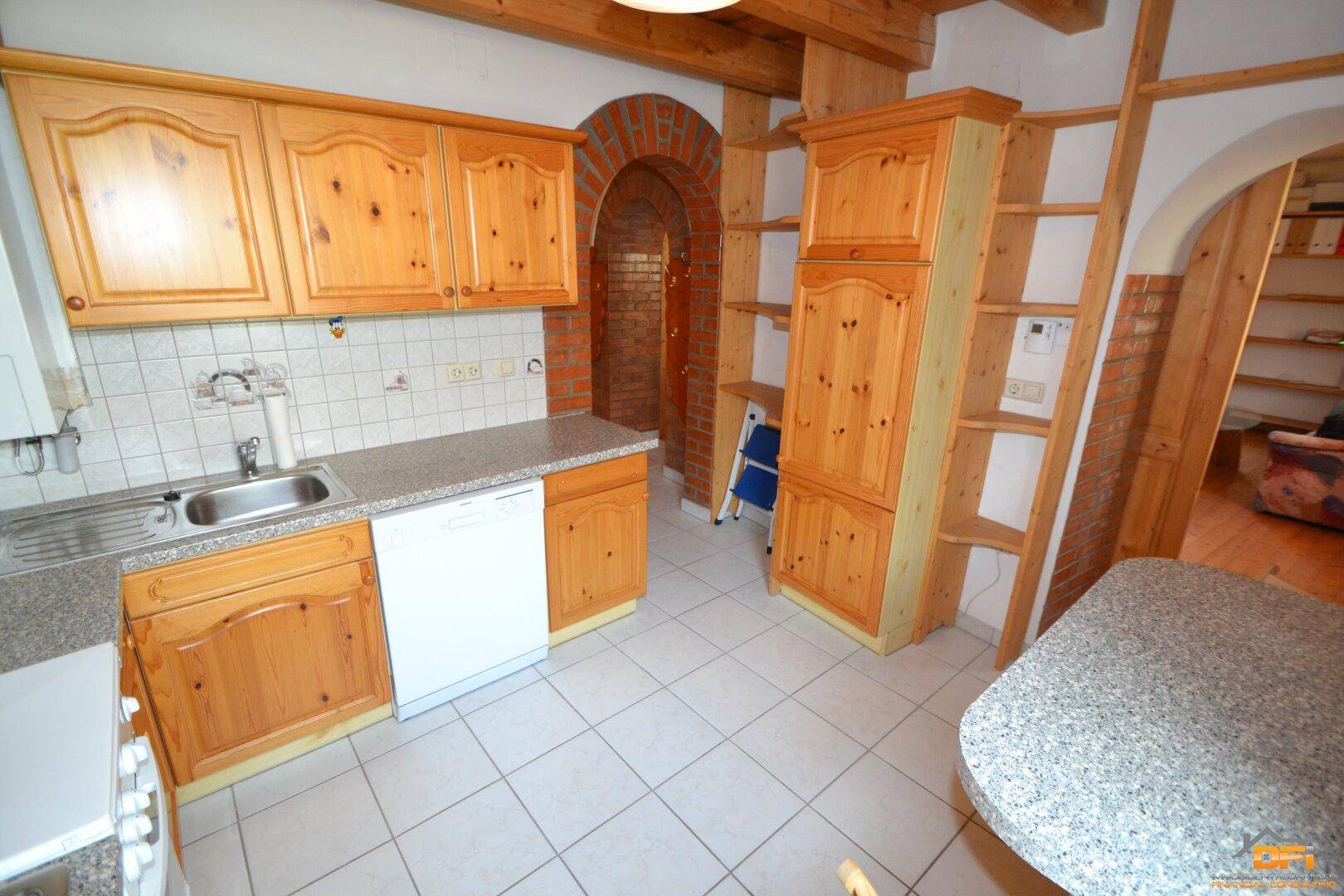 Einbauküche mit Holzfronten, Fliesenboden und Spülmaschine.