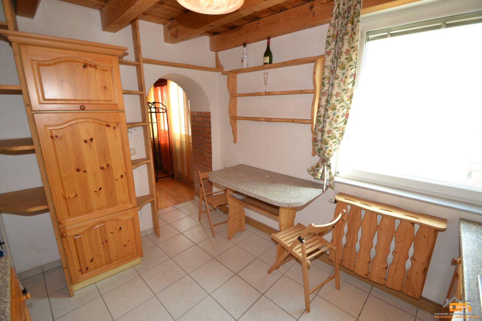 Gemütliche Küche mit Essbereich, Holzschränken und Fenster.