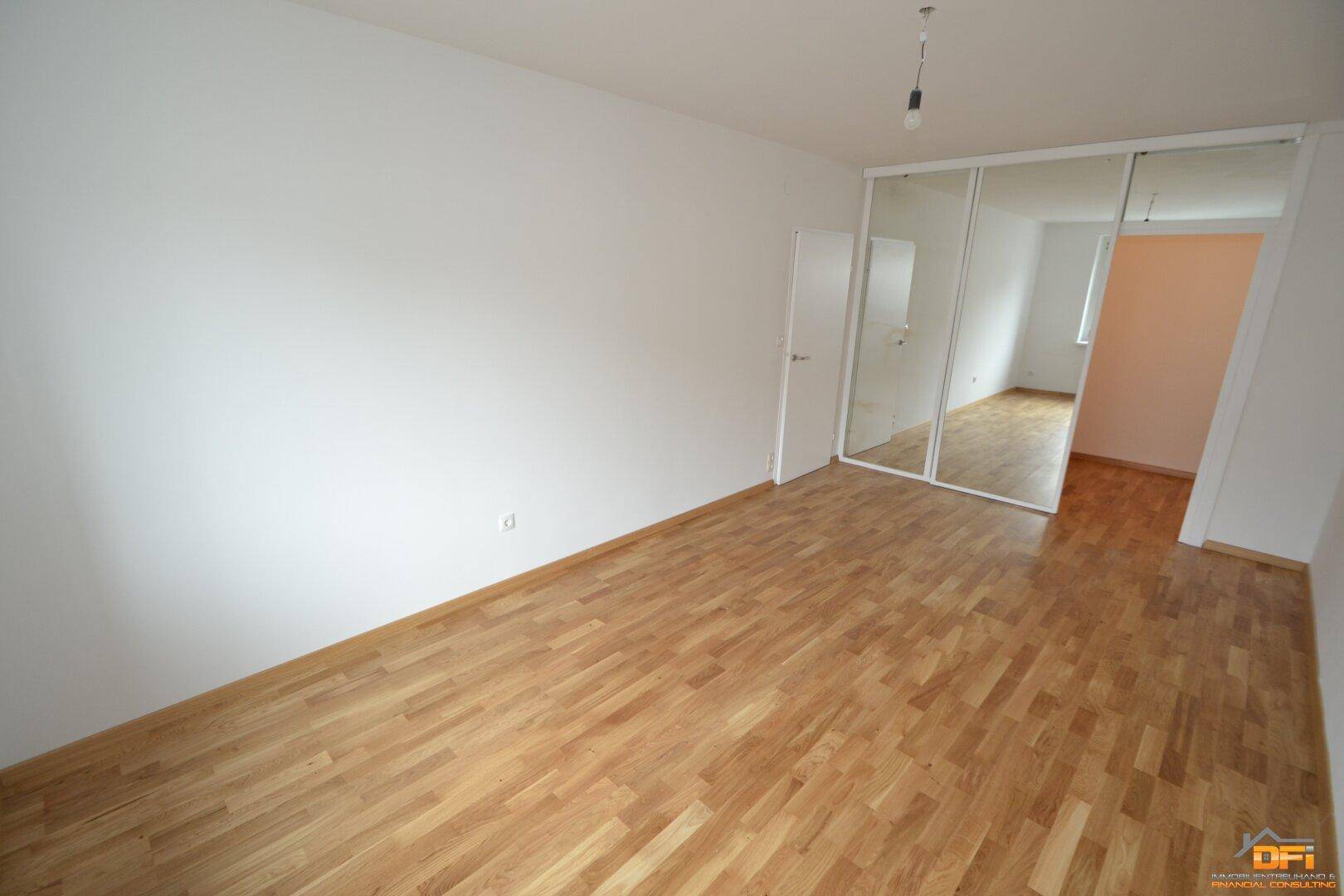 Helles Schlafzimmer mit Parkettboden und integrierten Spiegelschränken, bietet viel Stauraum.