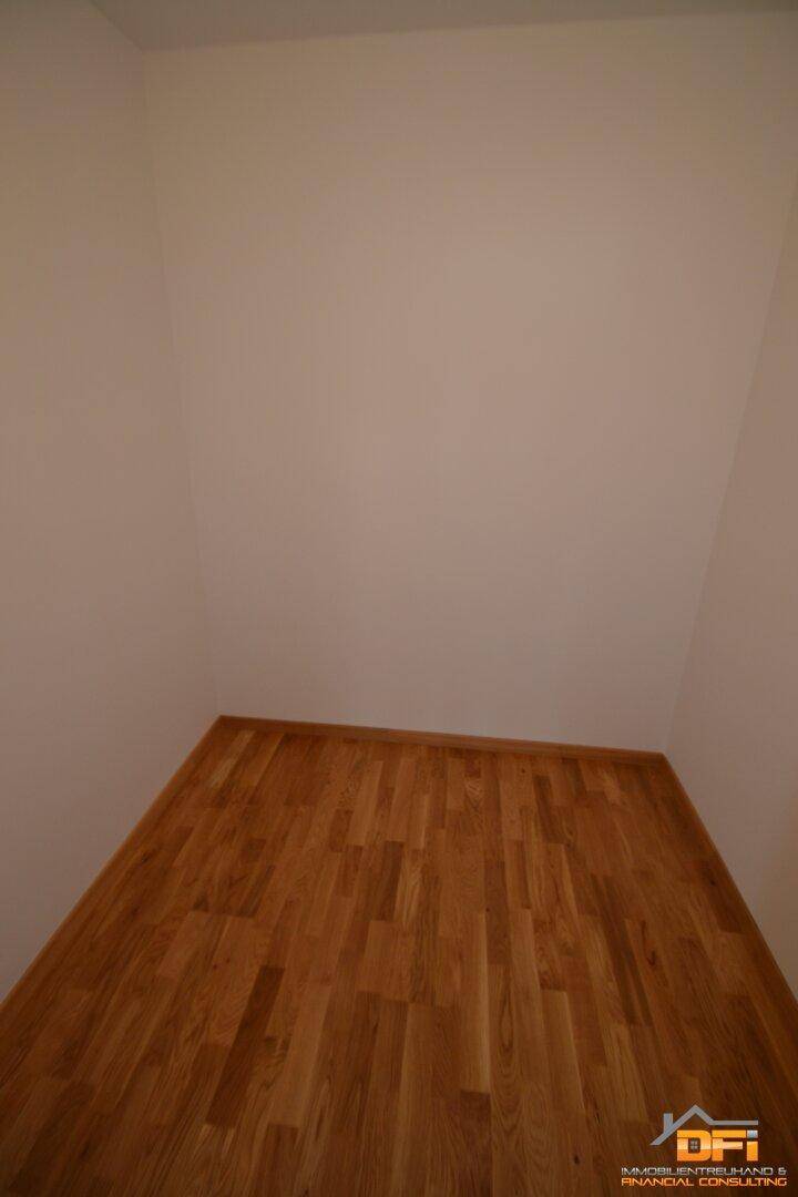 Kleiner Abstellraum oder begehbarer Kleiderschrank mit hellem Parkettboden.