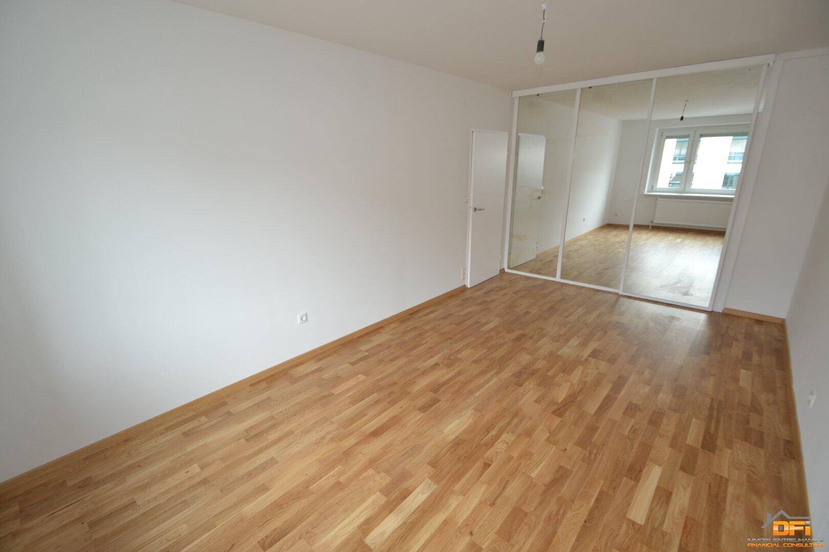 Schlafzimmer mit Parkettboden und großen Spiegelschränken, die den Raum optisch vergrößern.