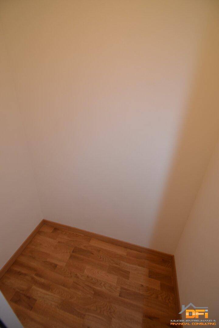 Kleiner Abstellraum oder begehbarer Kleiderschrank mit hellem Parkettboden.