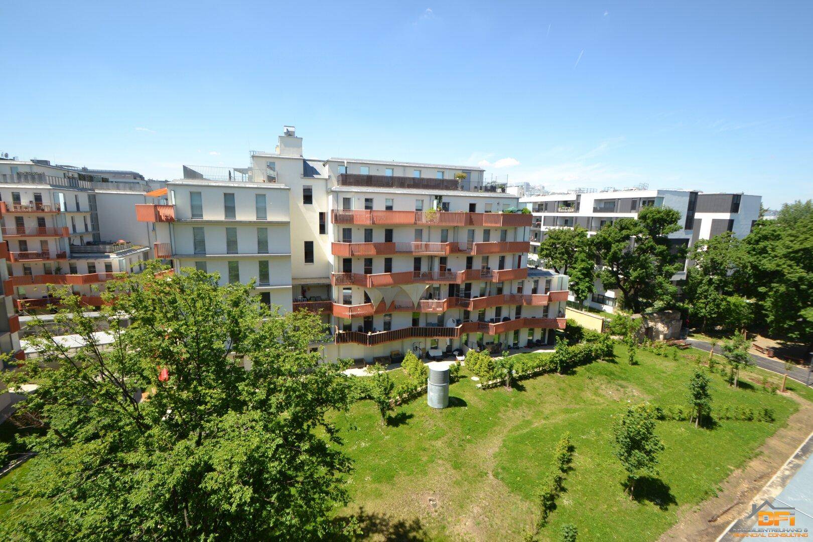 Moderne Wohnanlage mit mehreren Balkonen und gepflegten Grünflächen unter blauem Himmel.