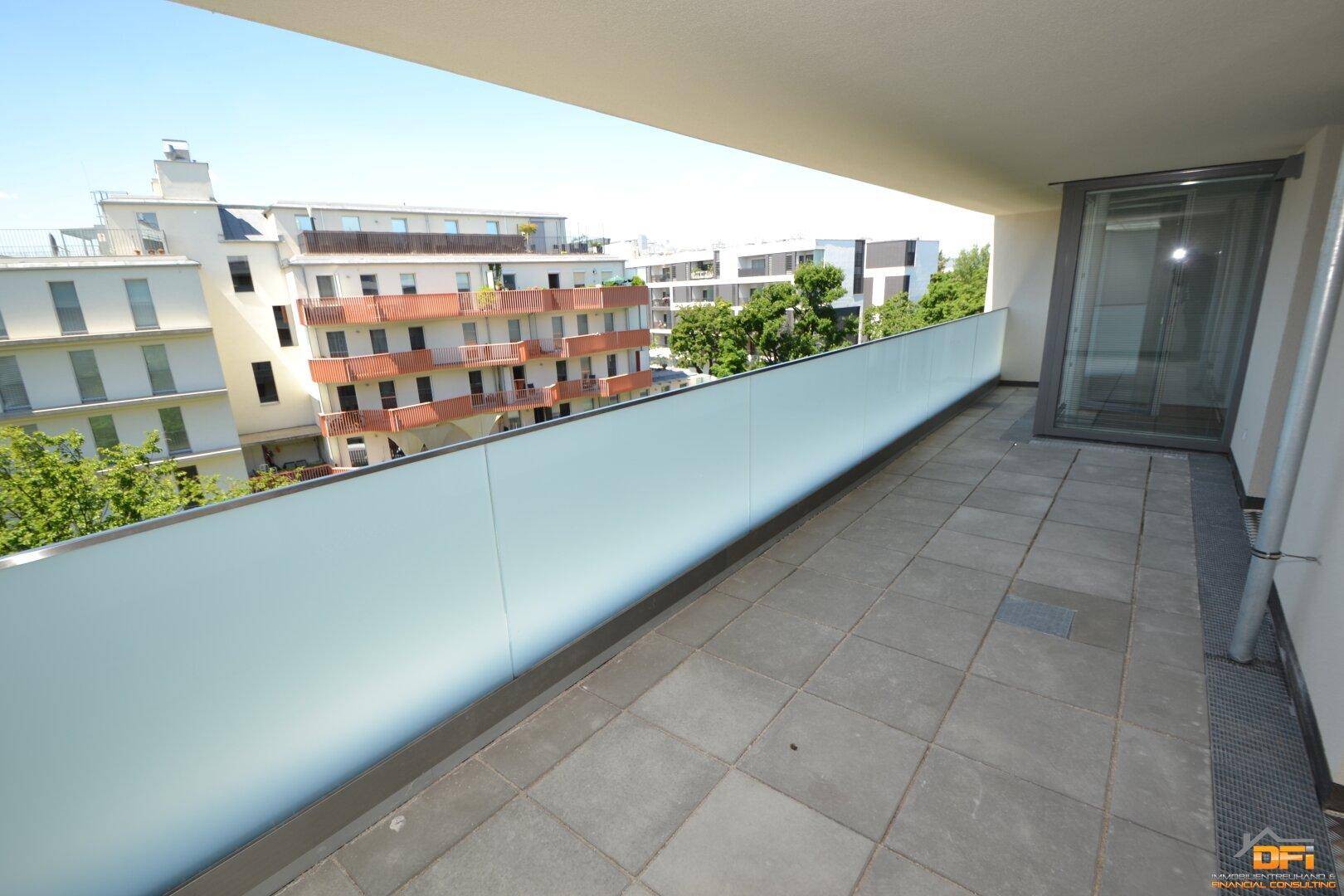 Langer Balkon mit Fliesenboden und undurchsichtiger Brüstung, bietet Privatsphäre und Weitblick.
