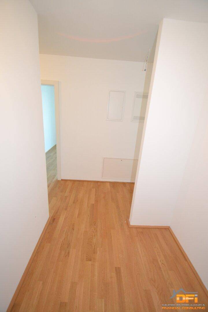 Heller Flur mit Parkettboden, der zu den verschiedenen Räumen der Wohnung führt.