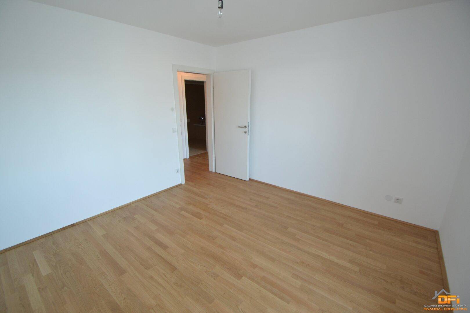 Leeres Schlafzimmer mit Parkettboden und weiß gestrichenen Wänden, bereit zur individuellen Gestaltung.