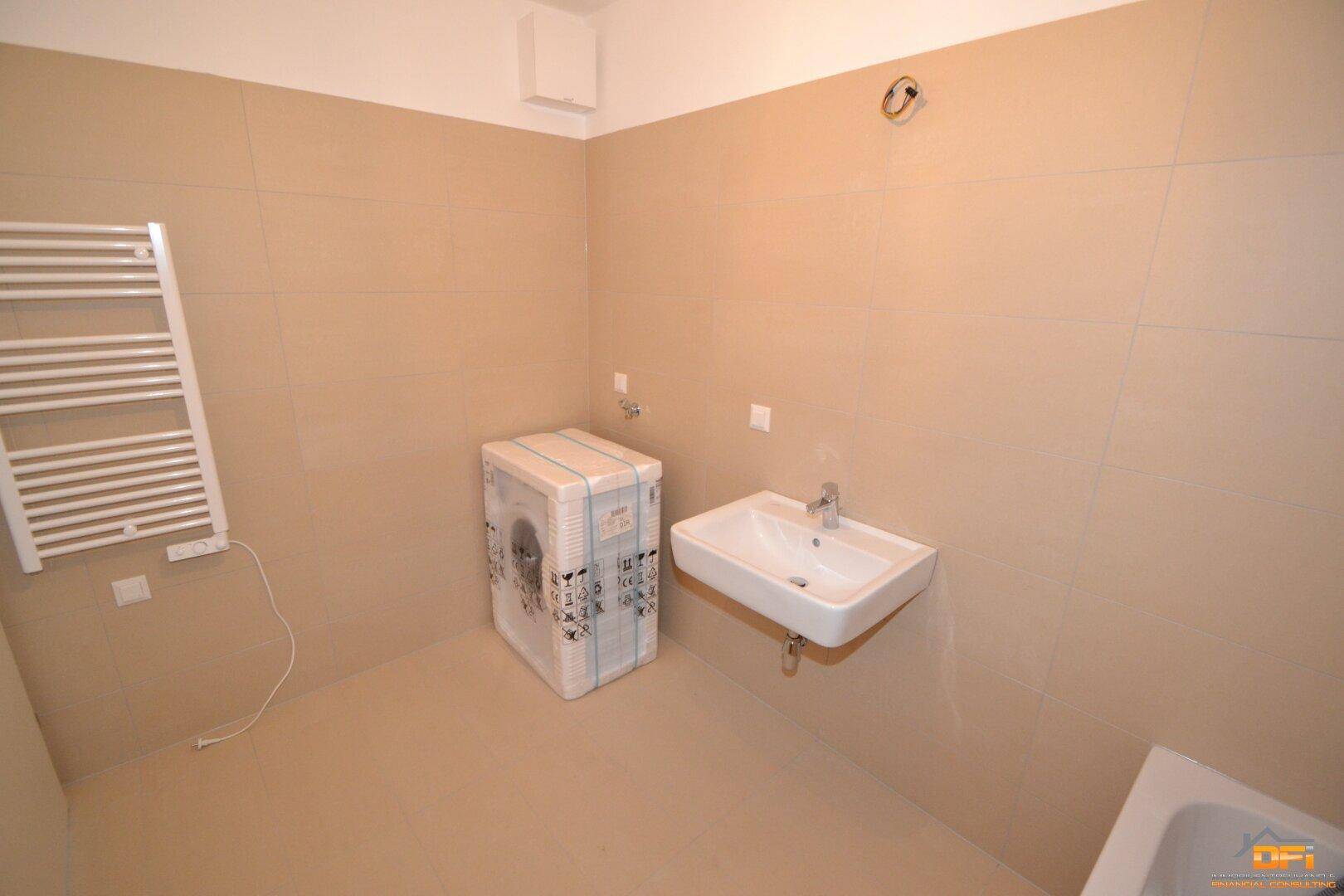 Modernes Badezimmer mit beigefarbenen Fliesen, Waschbecken und beheiztem Handtuchhalter.