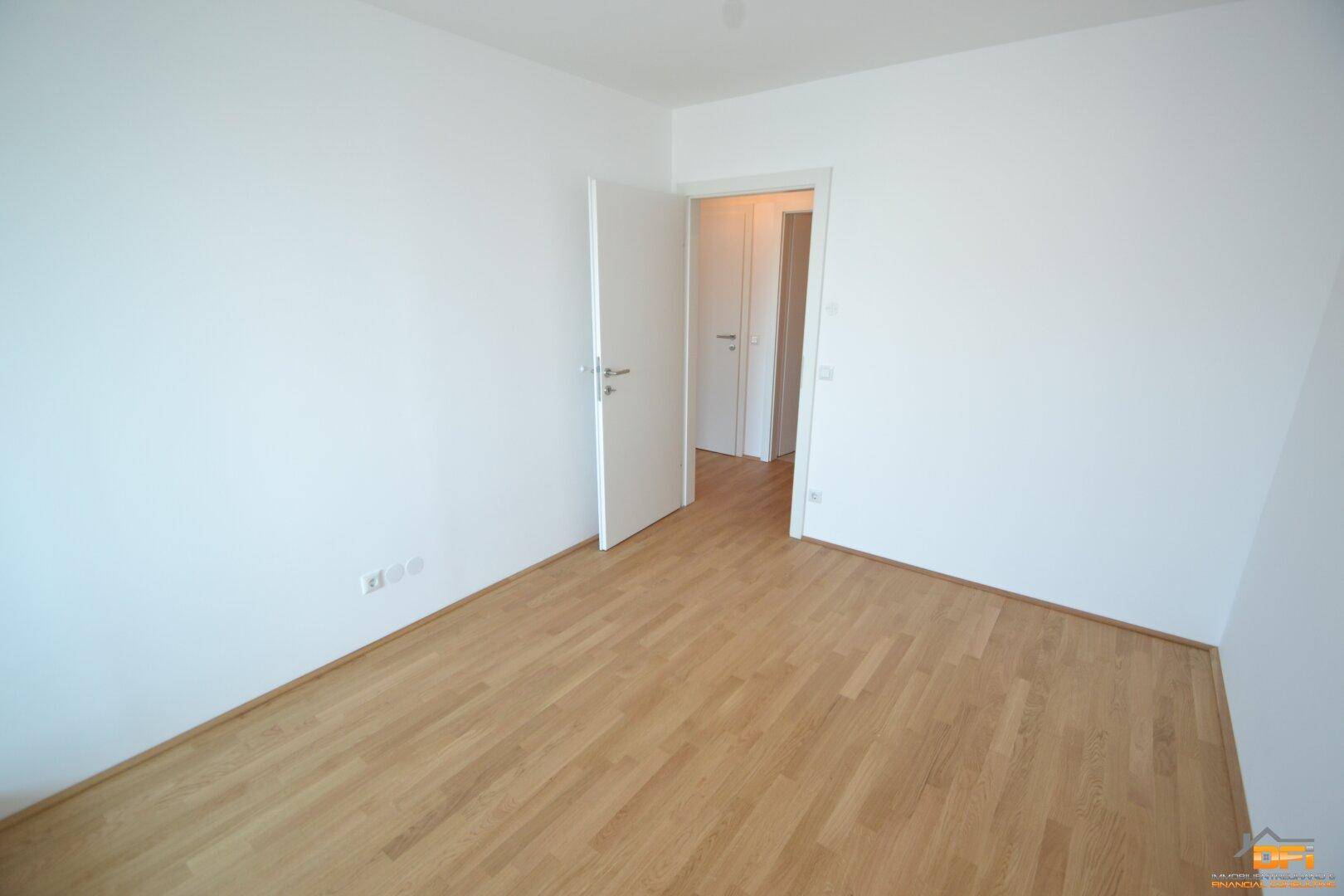 Leeres Schlafzimmer mit Parkettboden und weiß gestrichenen Wänden, bietet viel Gestaltungspotenzial.