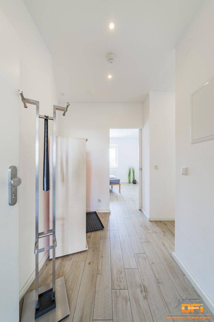 Heller Flur mit Holzoptik-Laminatboden und Garderobe, der zu weiteren Räumen führt.