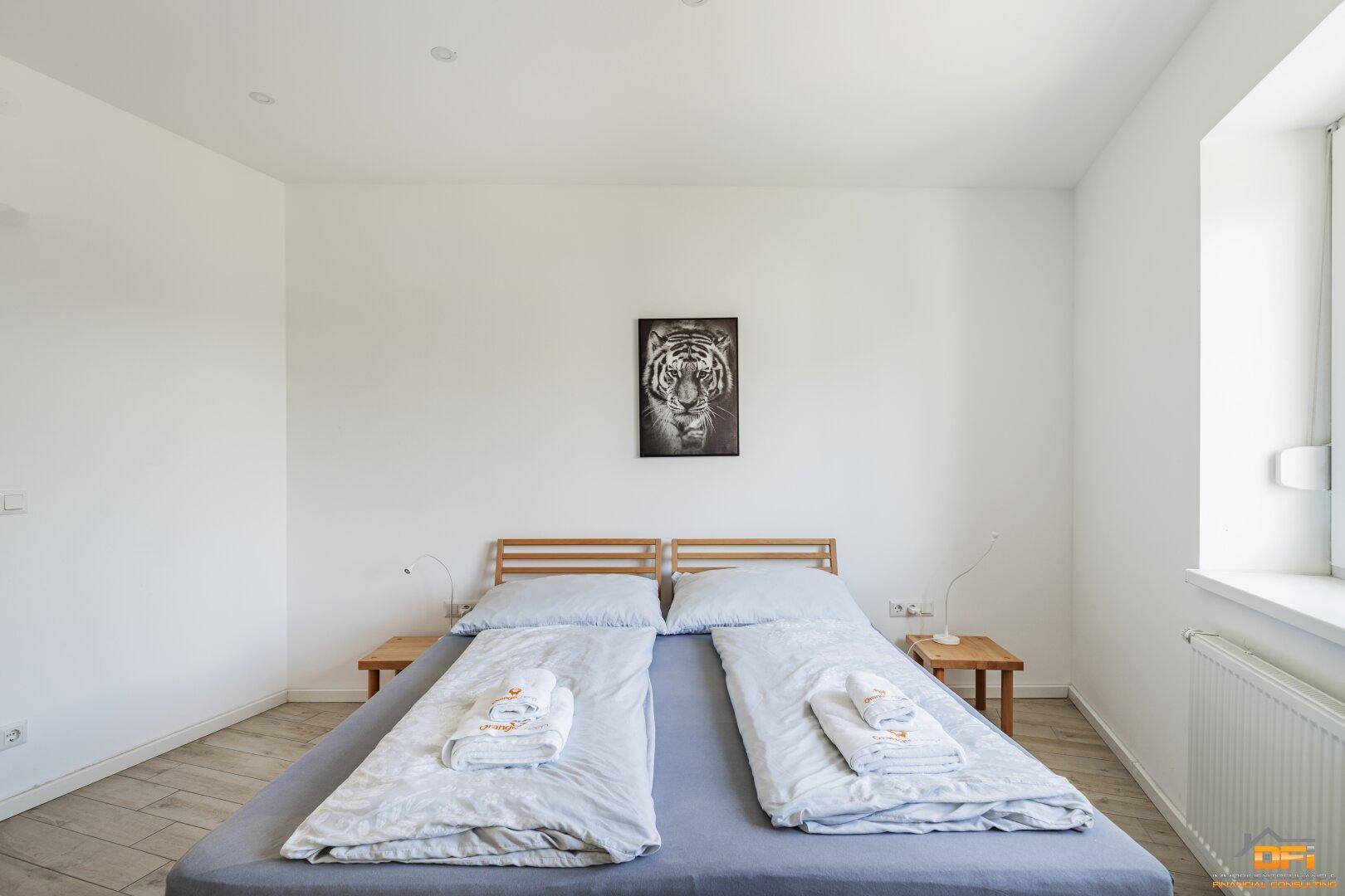 Schlafzimmer mit zwei Einzelbetten, die zu einem Doppelbett zusammengestellt sind, und Wanddekoration.