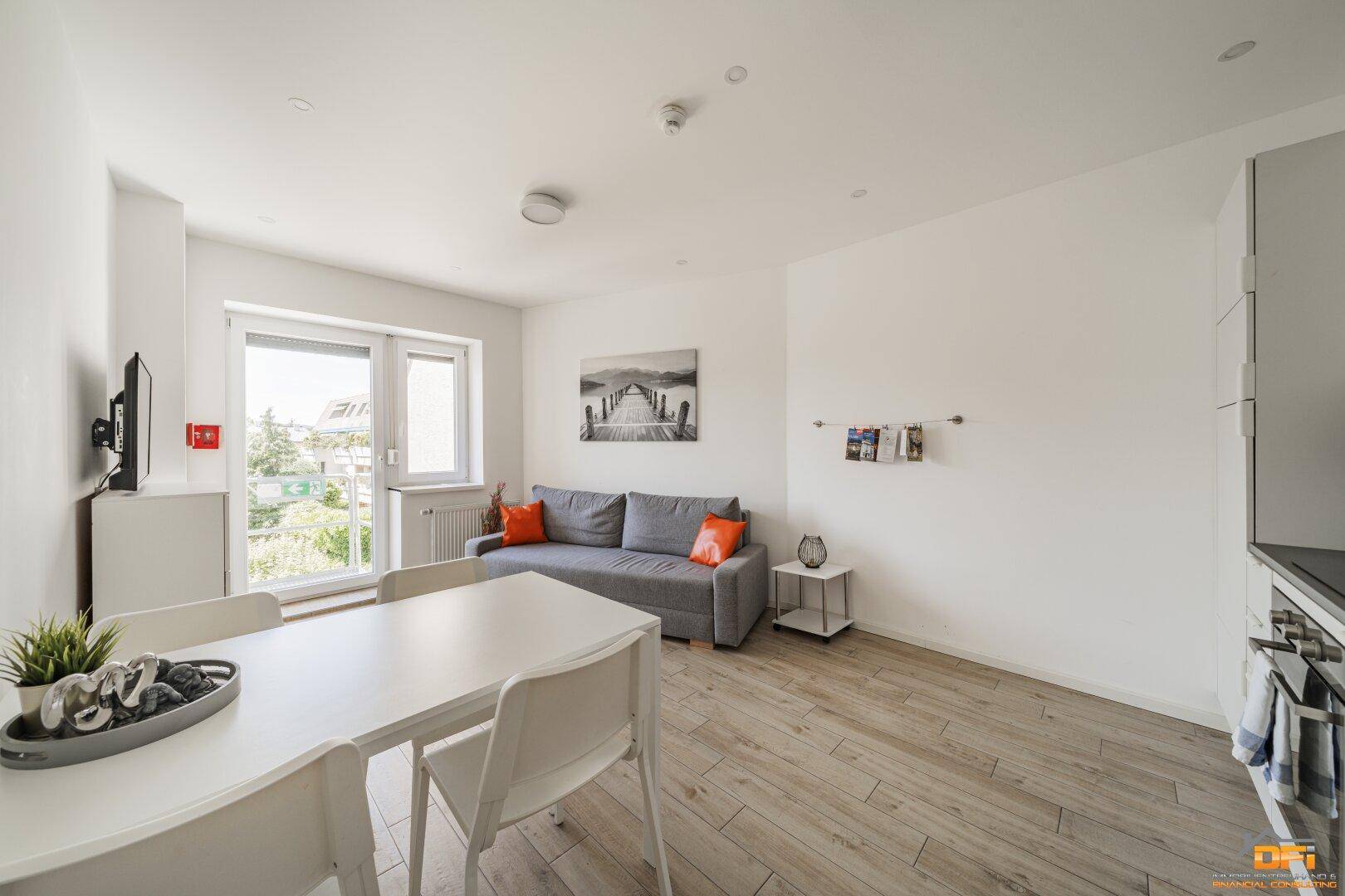 Kombinierter Wohn- und Essbereich mit Sofa, Esstisch und Blick auf die offene Küche.