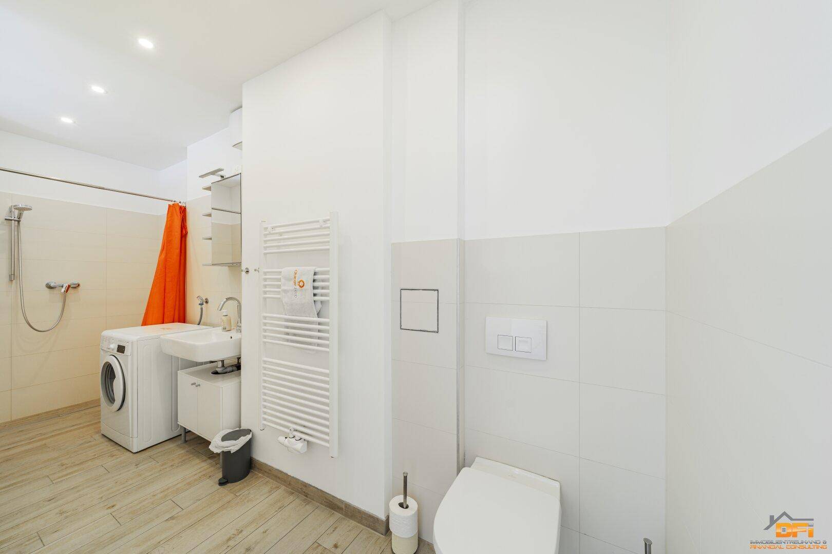Modernes Badezimmer mit Dusche, WC, Waschmaschine und beheiztem Handtuchhalter.