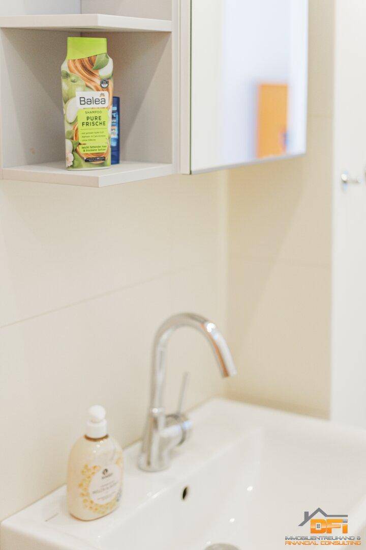 Detailansicht des Waschbeckens mit Wasserhahn und einem Spiegelschrank im Badezimmer.