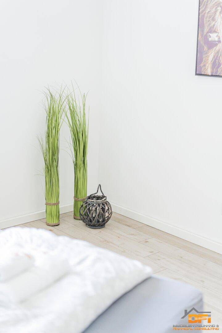 Detailansicht des Bodens im Schlafzimmer mit Dekoration und dem Bett im Vordergrund.