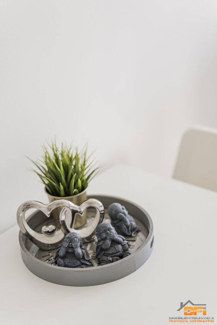 Nahaufnahme der Tischdekoration mit Buddha-Figuren und einem kleinen grünen Pflänzchen.