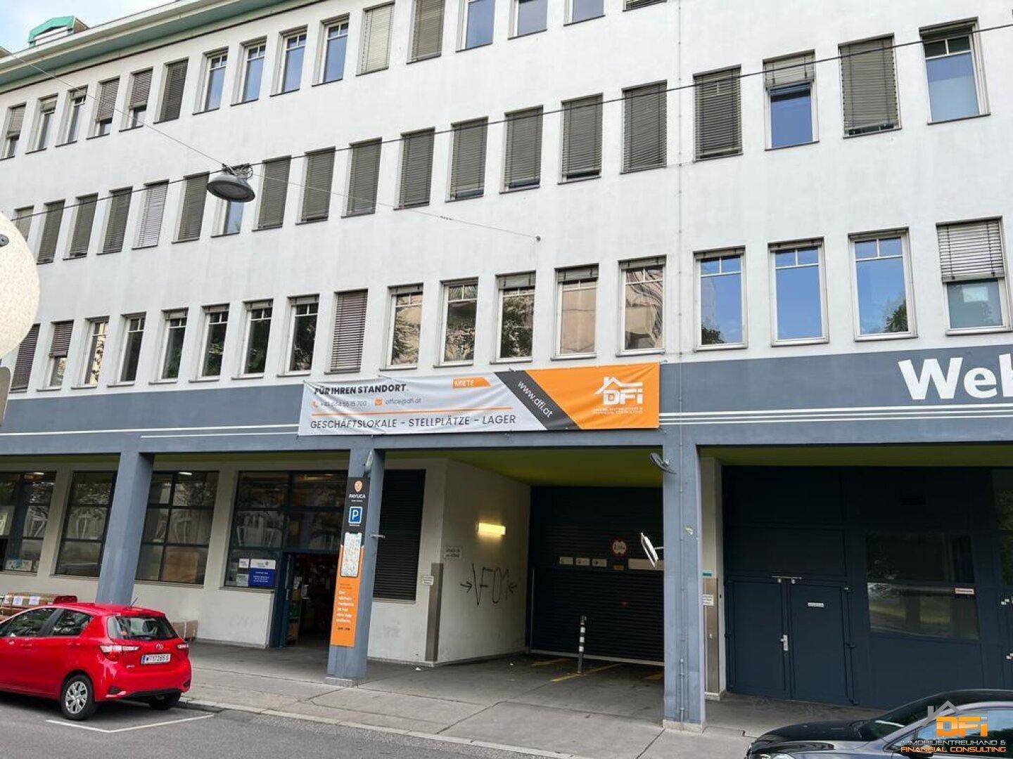 Fassade eines modernen Geschäftsgebäudes mit vielen Fenstern und einem Eingangsbereich im Erdgeschoss.