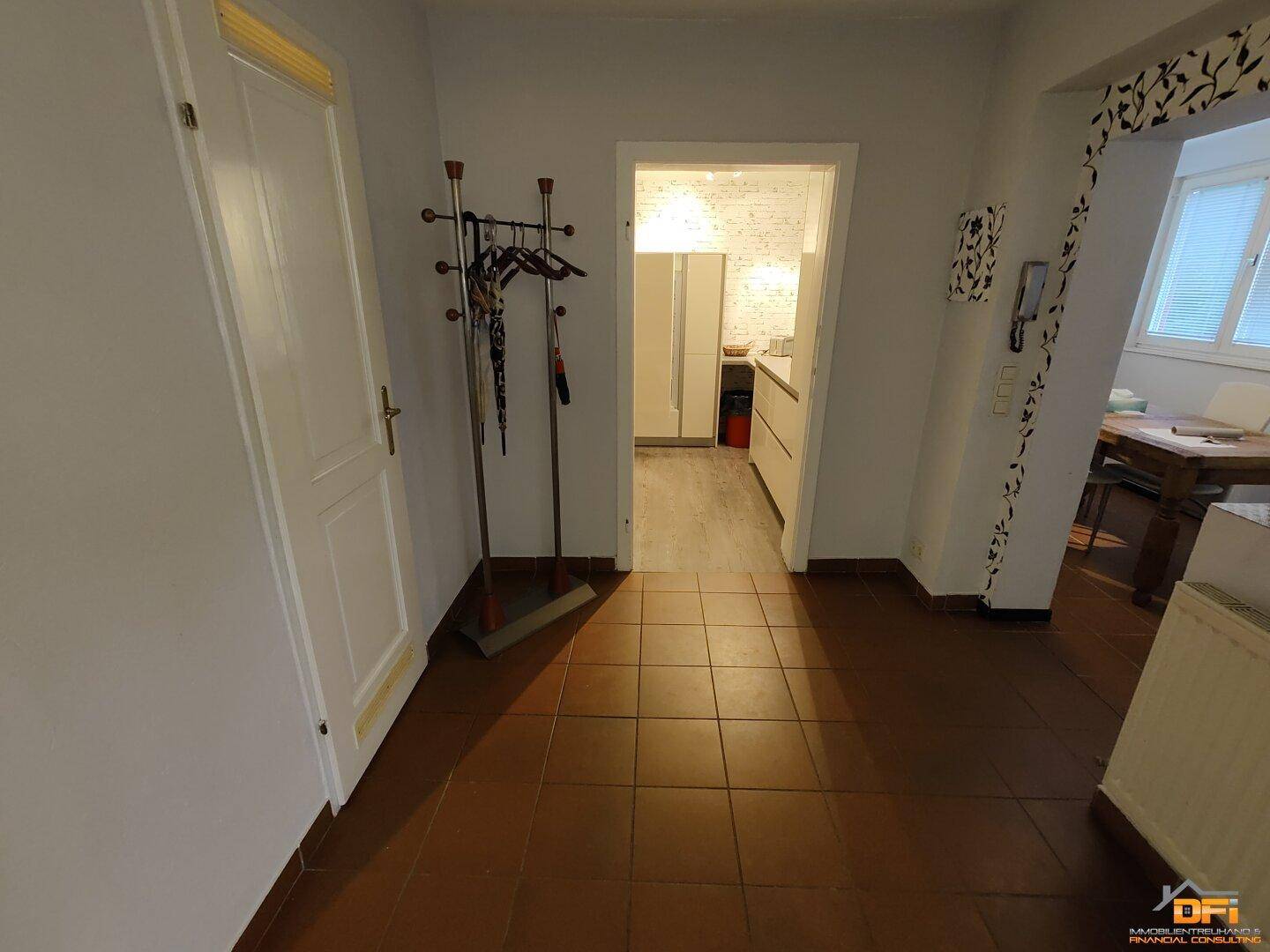 Flur mit Terrakottafliesen, Garderobe und Zugang zur Küche und Essbereich.