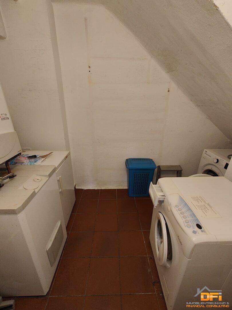 Hauswirtschaftsraum mit Waschmaschine, Trockner und schrägen Wänden im Dachgeschoss.