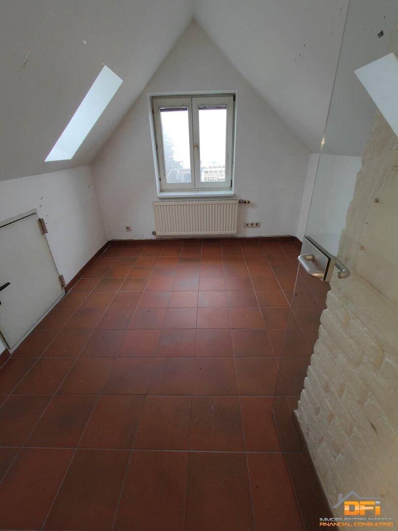 Dachbodenraum mit Terrakottafliesen, Dachfenster und schrägen Wänden.
