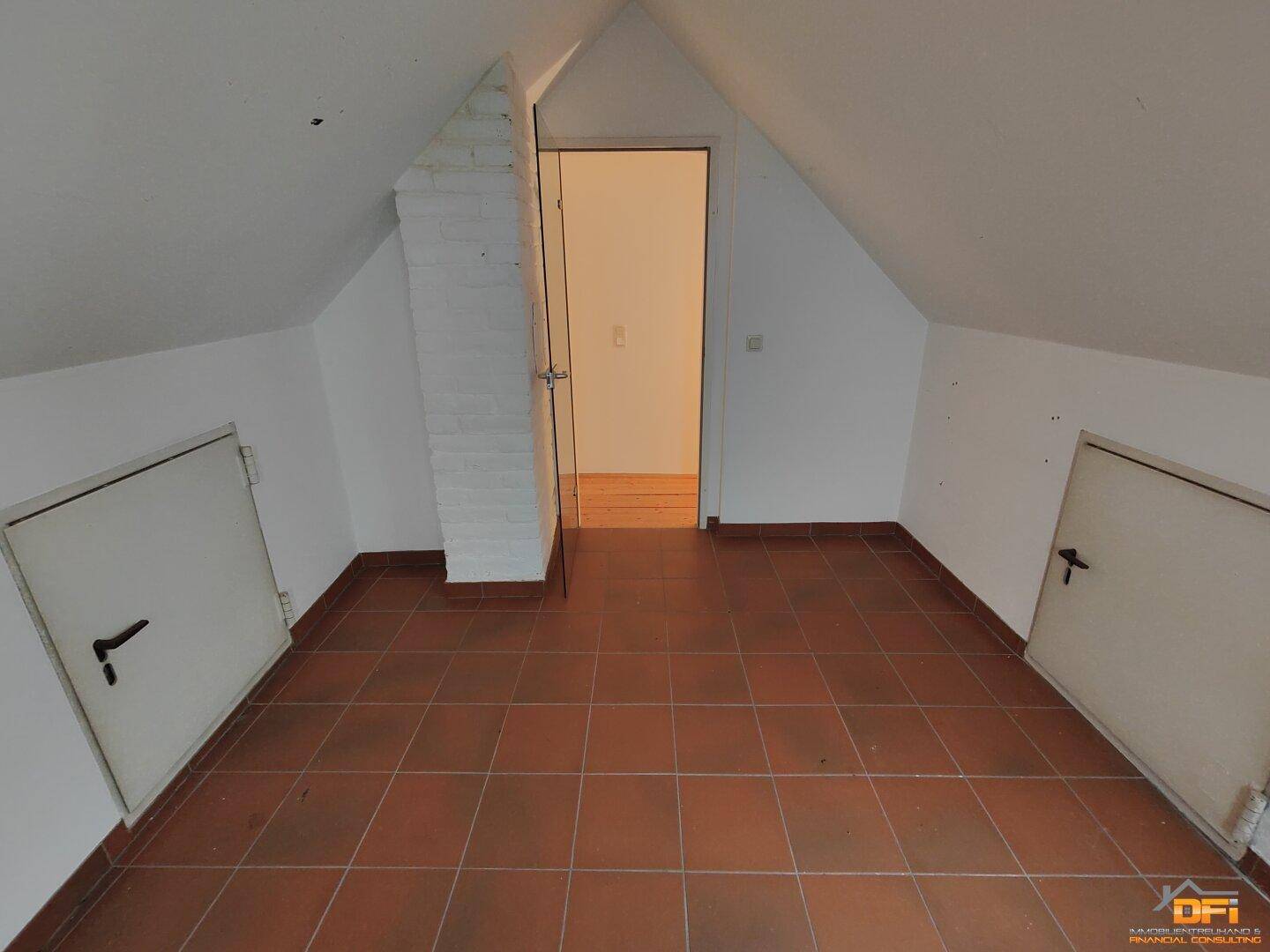 Geräumiger Dachboden mit Terrakottafliesen, Dachschrägen und Zugangstüren.
