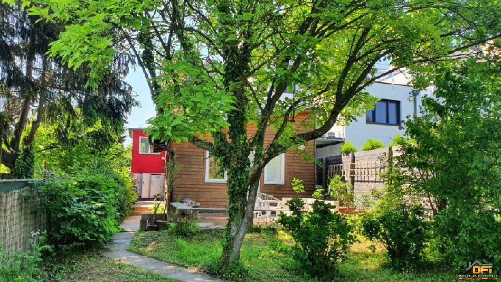 Idyllischer Garten mit altem Baumbestand und einem kleinen Holzhaus im Grünen.