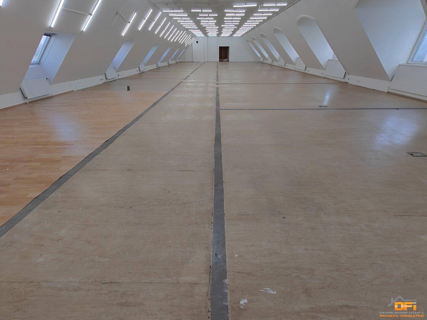 Detailansicht des Bodens im großen Raum mit unterschiedlichen Bodenbelägen und Markierungen.