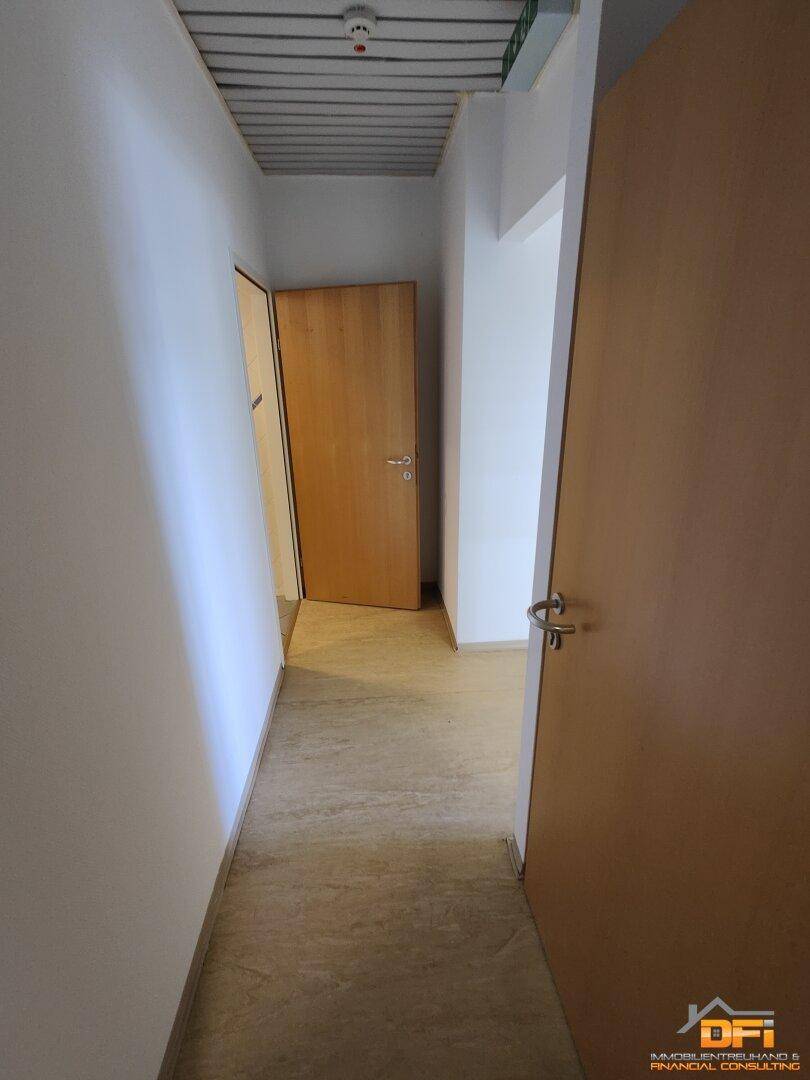 Schmaler Flur mit Holztüren und einfacher Deckenbeleuchtung.