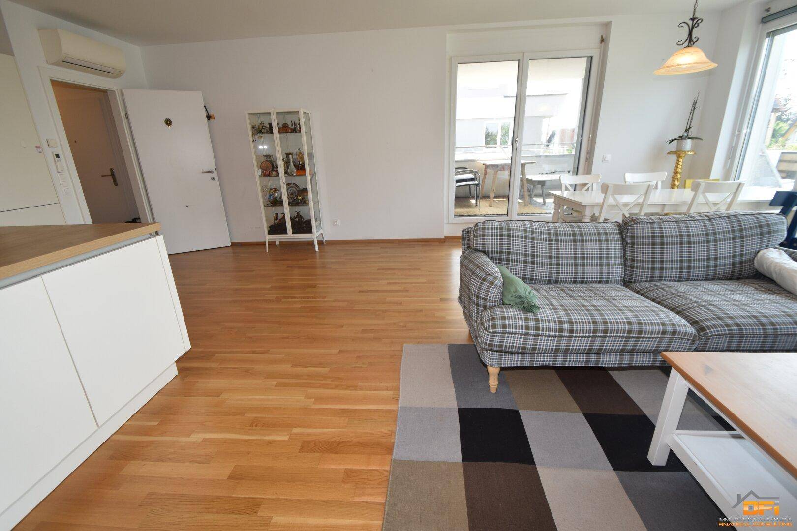 Geräumiger Wohn-Essbereich mit offener Küche, Holzboden und Zugang zum Außenbereich.