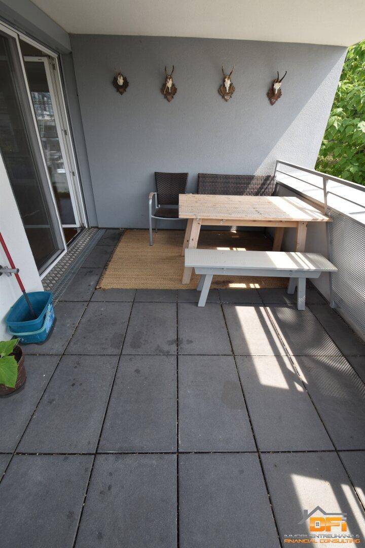 Balkon mit Fliesenboden, einfacher Sitzgelegenheit und traditionellen Geweih-Dekorationen an der Wand.