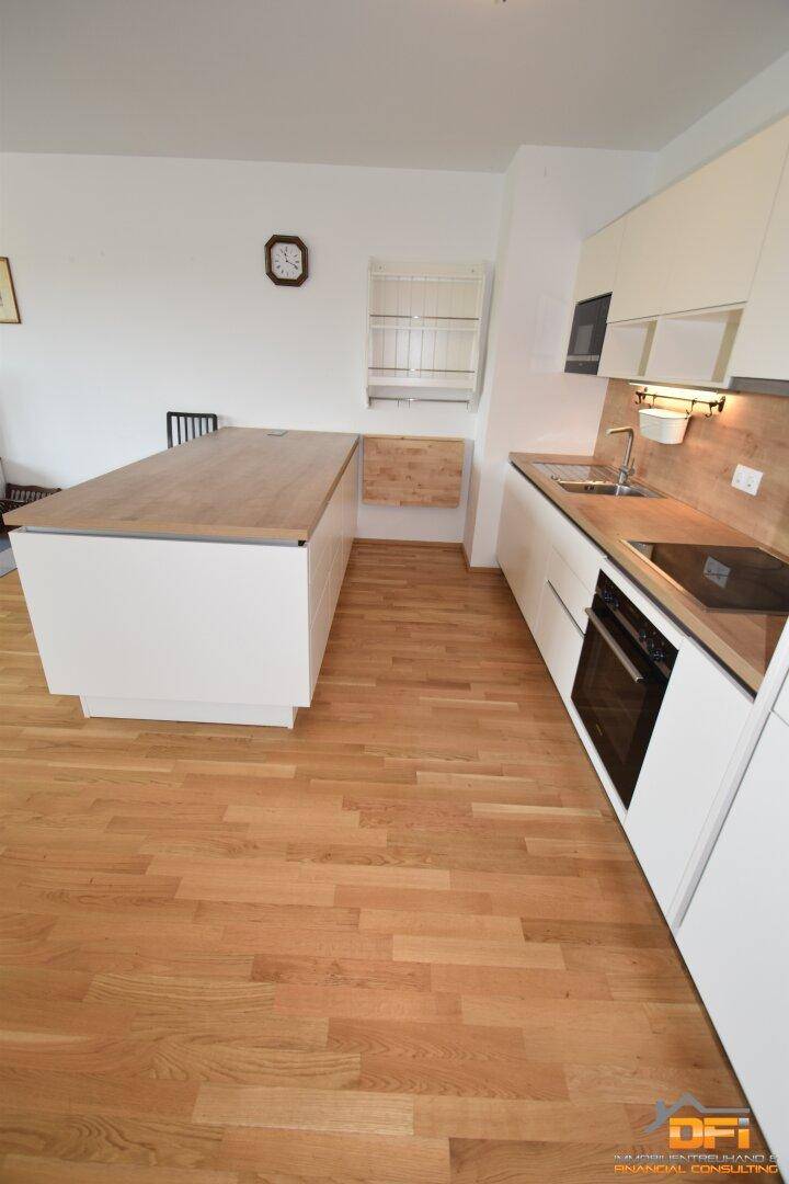 Helle Küche mit Kücheninsel, Holzboden und weißen Schränken, die viel Arbeitsfläche bietet.