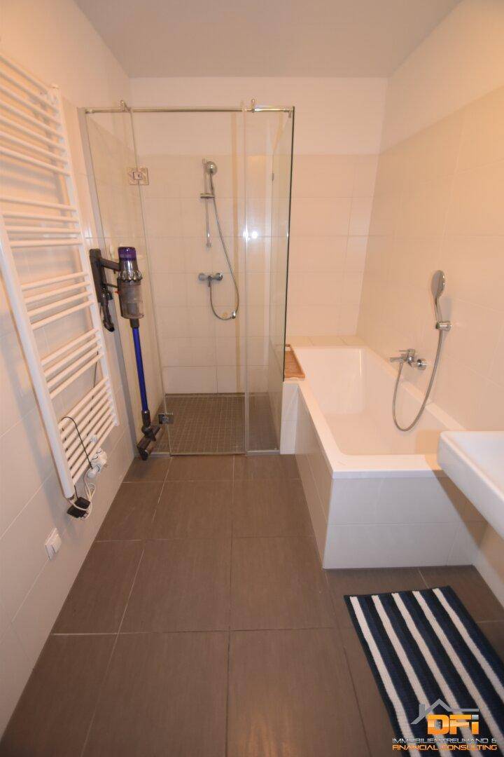 Modernes Badezimmer mit Fliesenboden, Badewanne, Duschkabine und beheiztem Handtuchhalter.