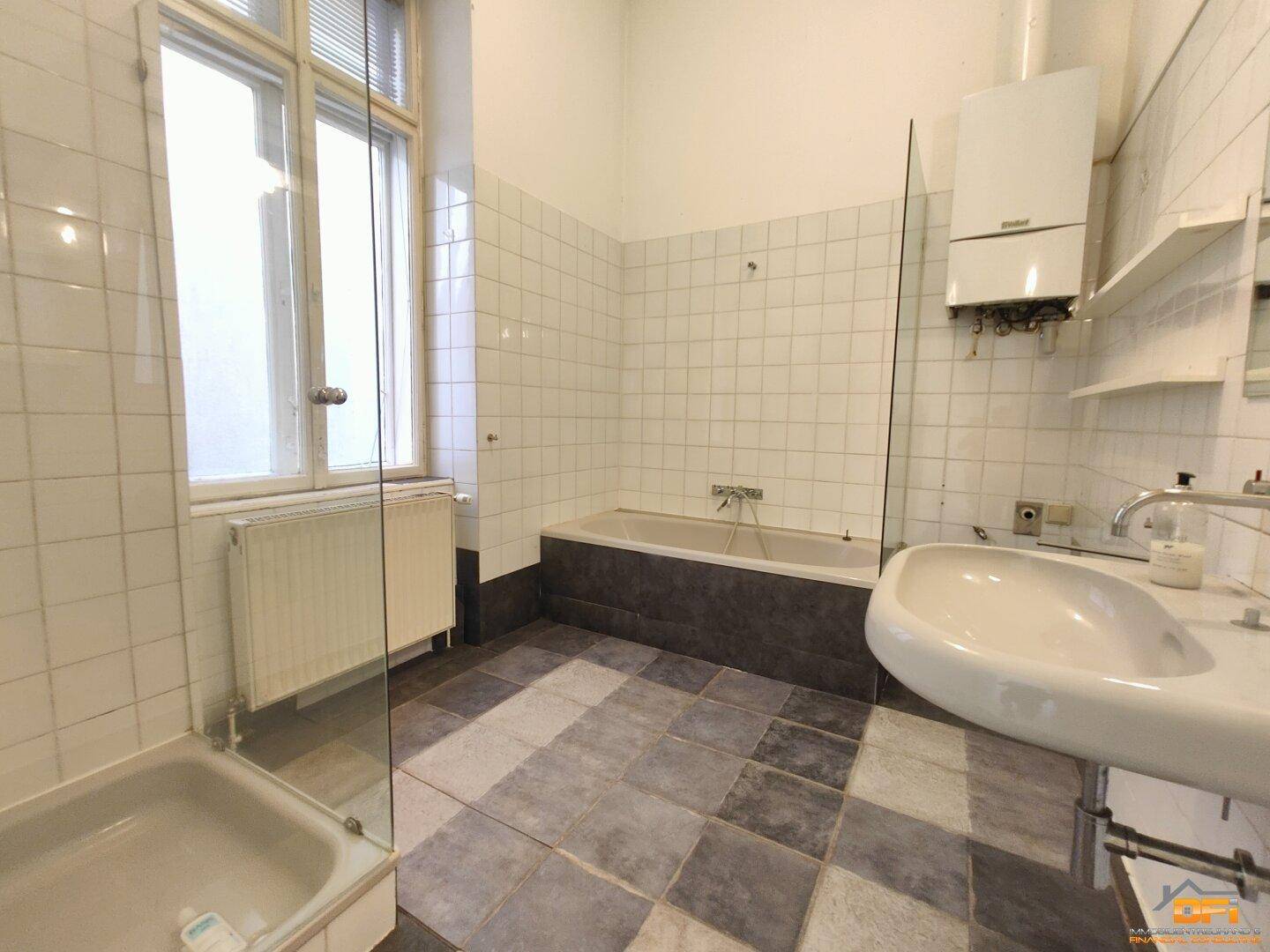 Badezimmer mit Badewanne, Dusche und Waschbecken, gefliest und mit Fenster.