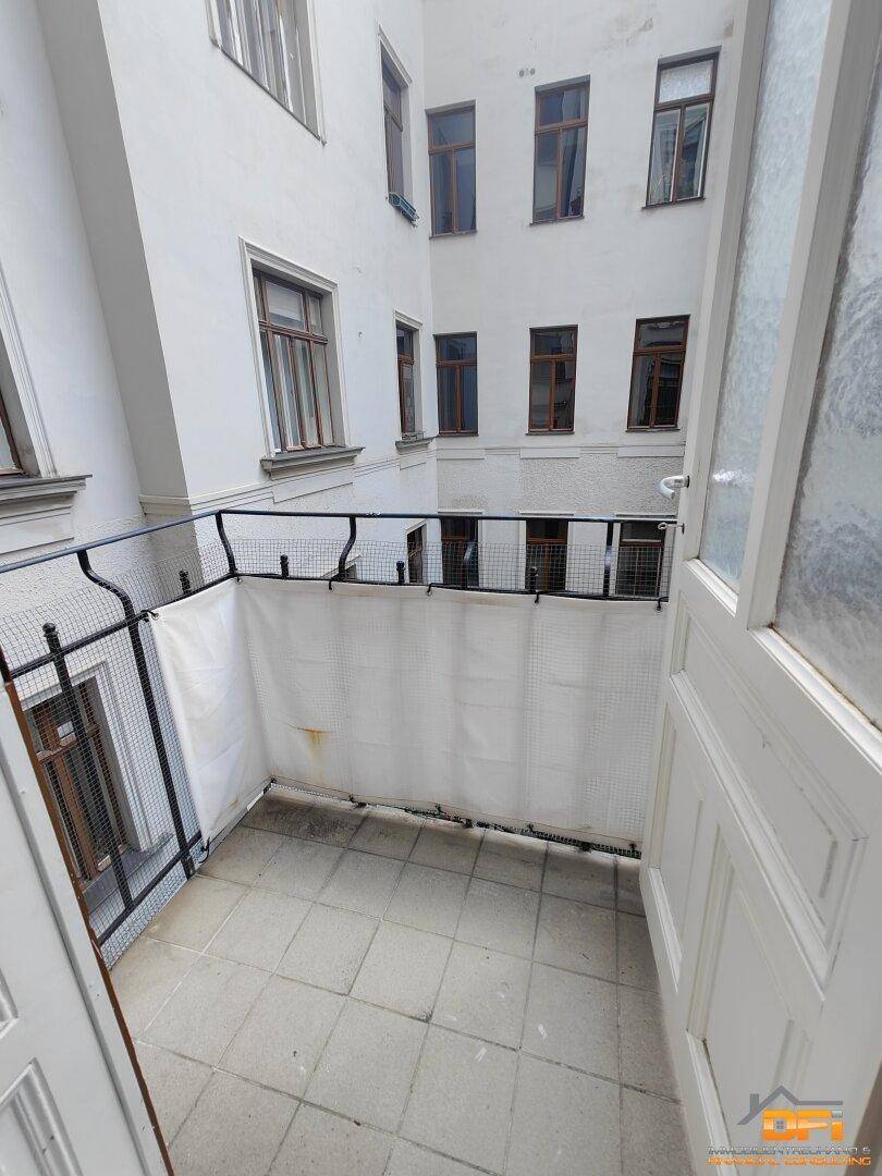 Kleiner Balkon mit Fliesenboden und Blick auf den Innenhof des Gebäudes.