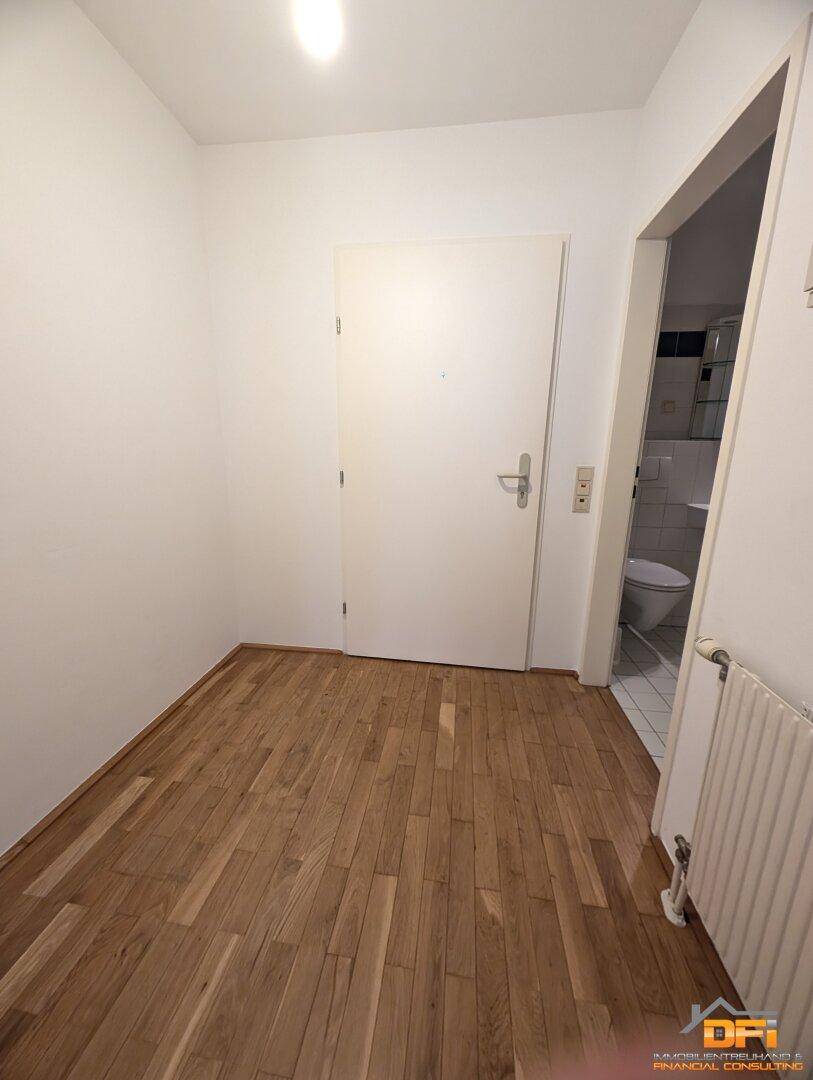 Heller Eingangsbereich mit Parkettboden und Zugang zu weiteren Räumen, inklusive Gästetoilette.