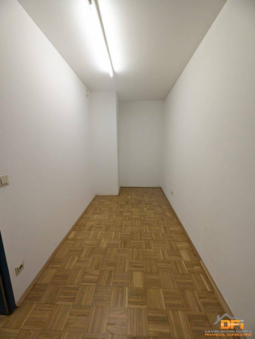 Kleiner, schmaler Raum mit Parkettboden und weißen Wänden, ideal als Abstellraum.