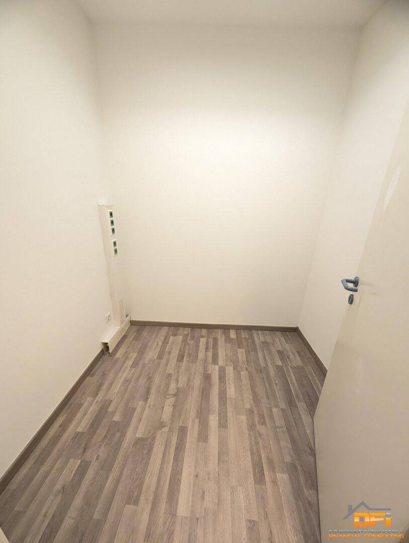 Kleiner, leerer Raum mit hellem Holzoptikboden und weißen Wänden, ideal als Technik- oder Abstellraum.