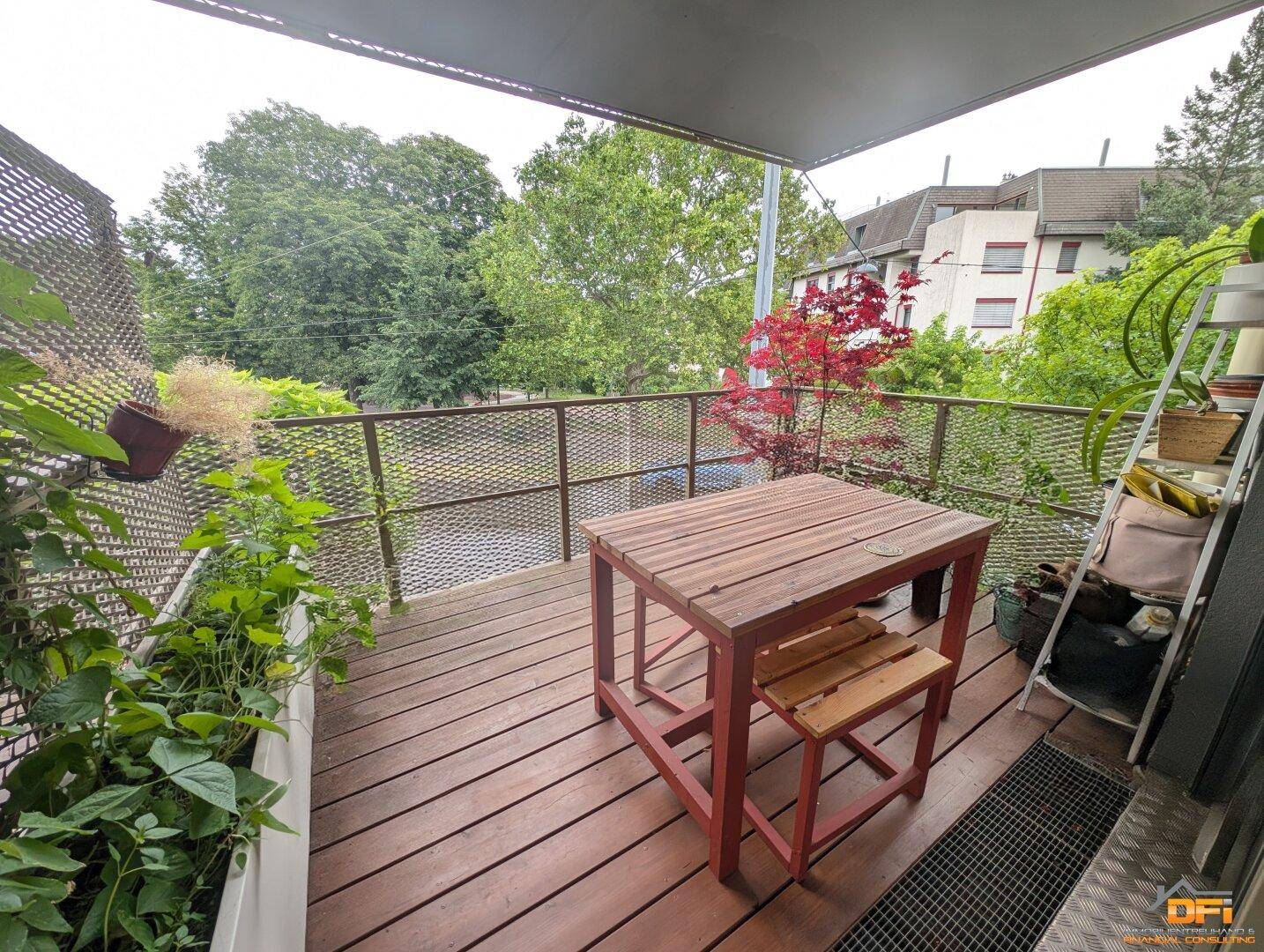 Gemütlicher Balkon mit Holzboden, Sitzgelegenheiten und Blick ins Grüne.