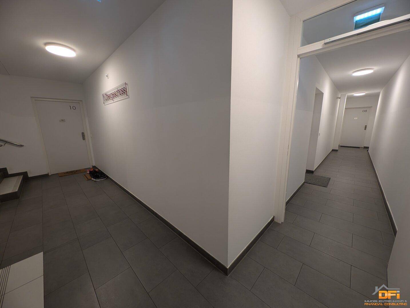 Heller Gemeinschaftsflur mit Fliesenboden und Zugang zu den einzelnen Wohneinheiten.