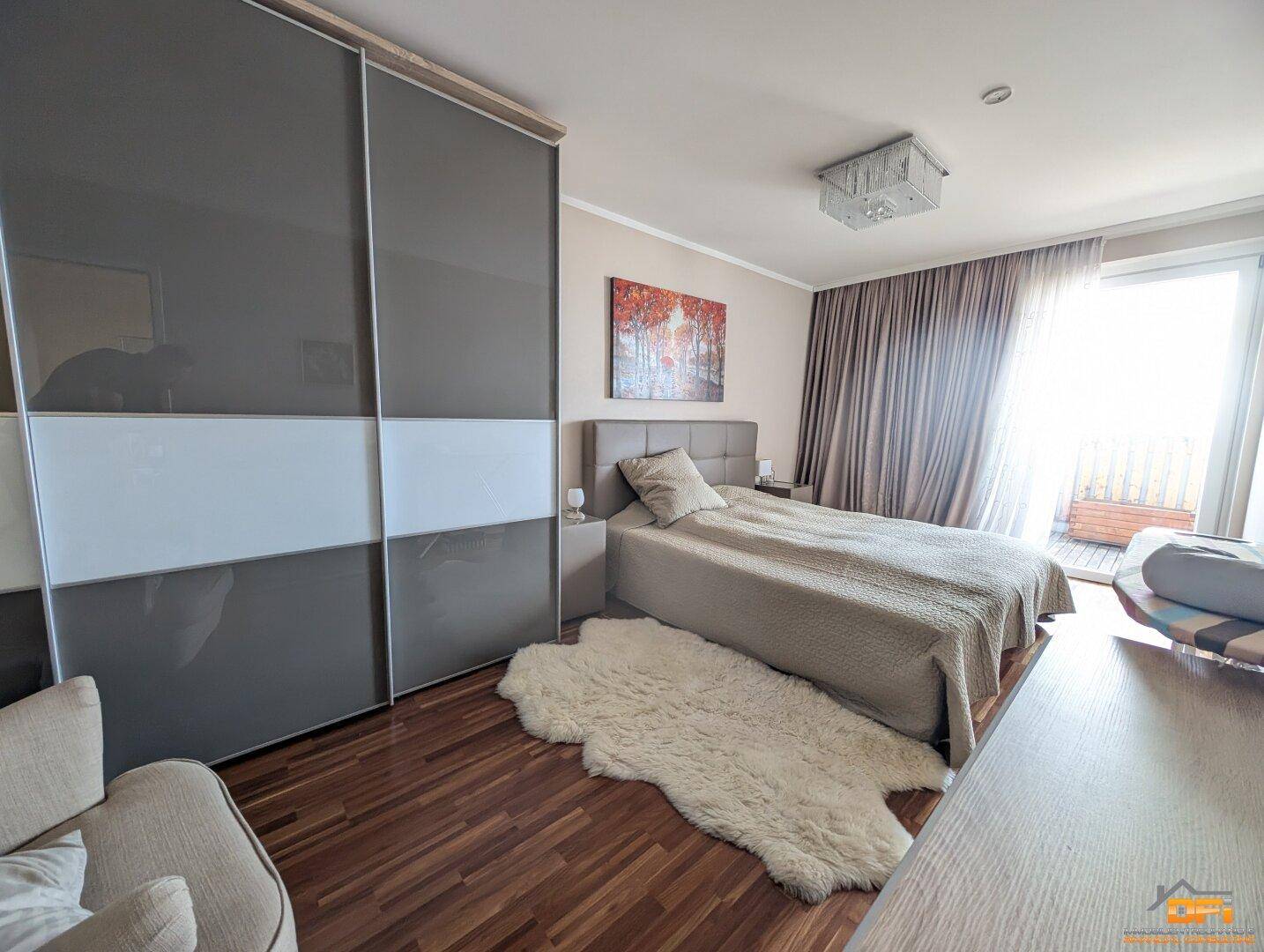 Helles Schlafzimmer mit großem Bett, Schiebetürenschrank und direktem Zugang zum Balkon.