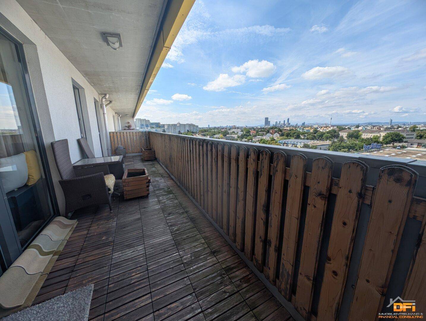 Balkon mit Holzboden und beeindruckendem Blick auf die Skyline der Stadt und die Umgebung.
