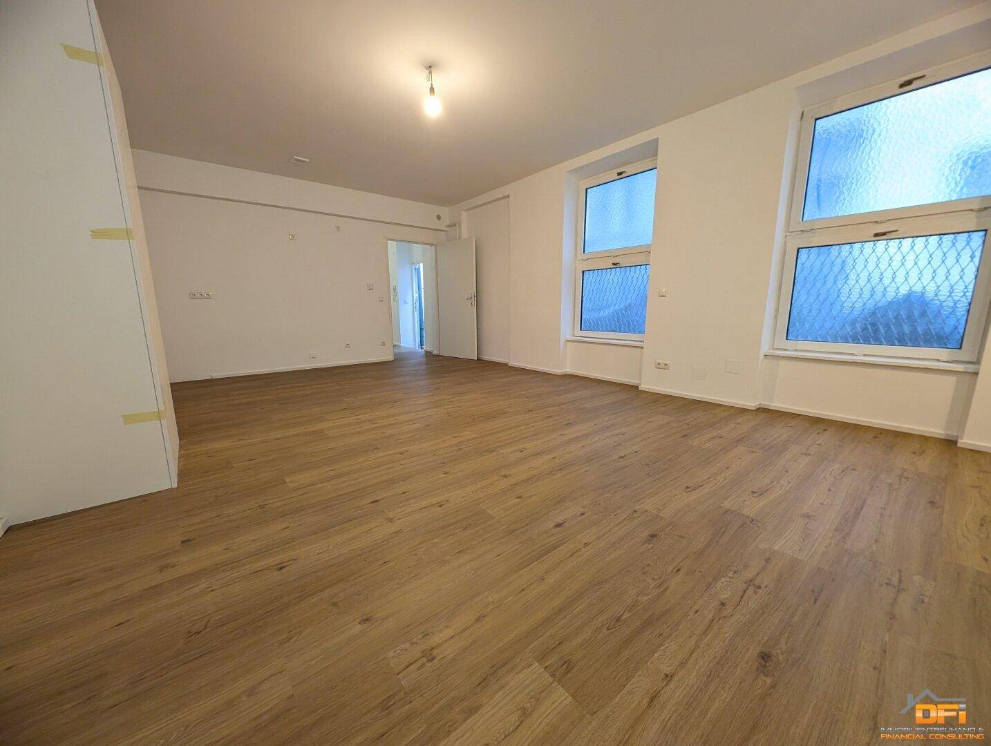 Großes, helles Zimmer mit Laminatboden und mehreren Fenstern, vielseitig nutzbar.
