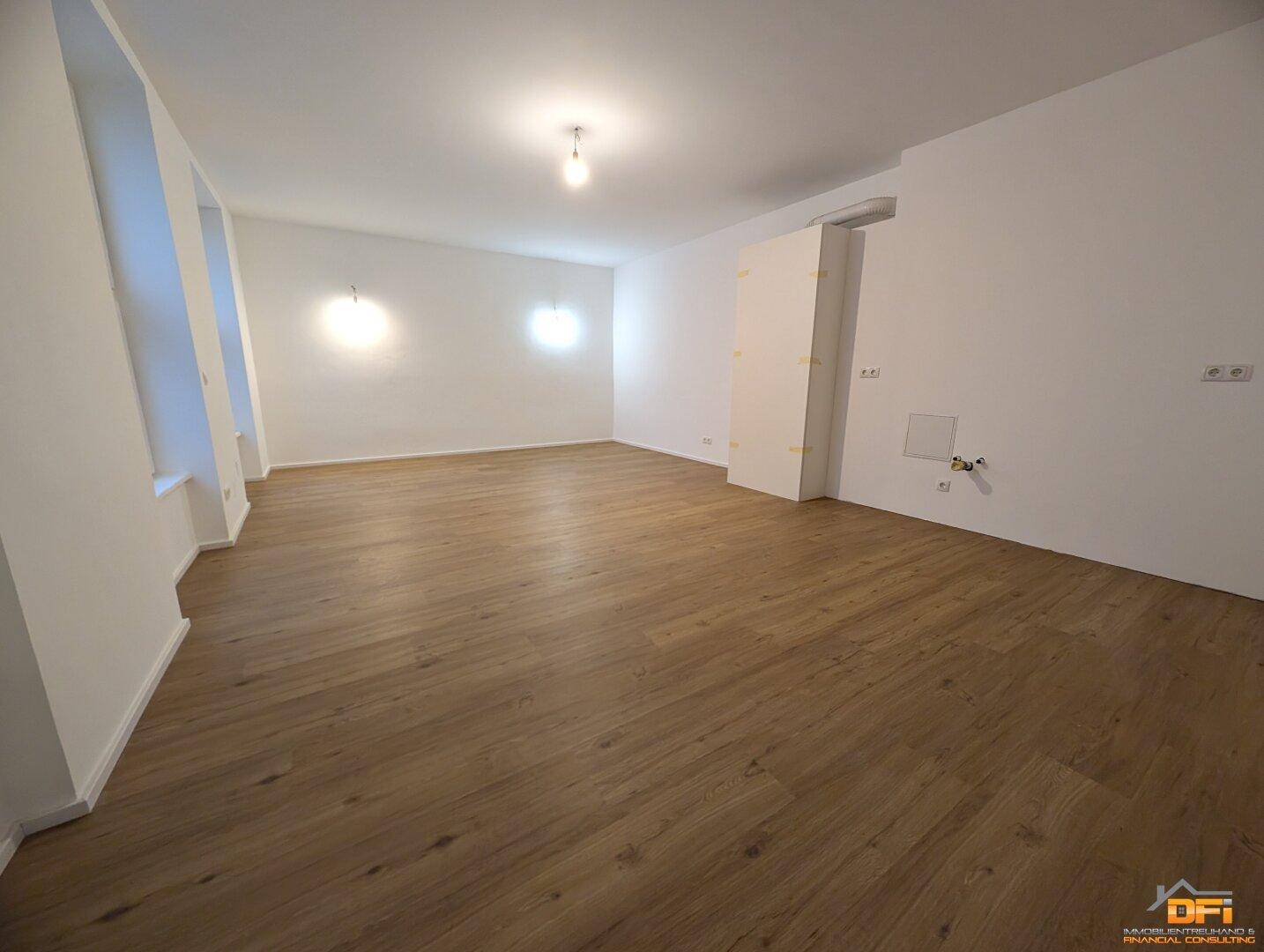 Geräumiges Zimmer mit hellem Laminatboden und weißen Wänden, ideal für Wohn- oder Schlafbereich.