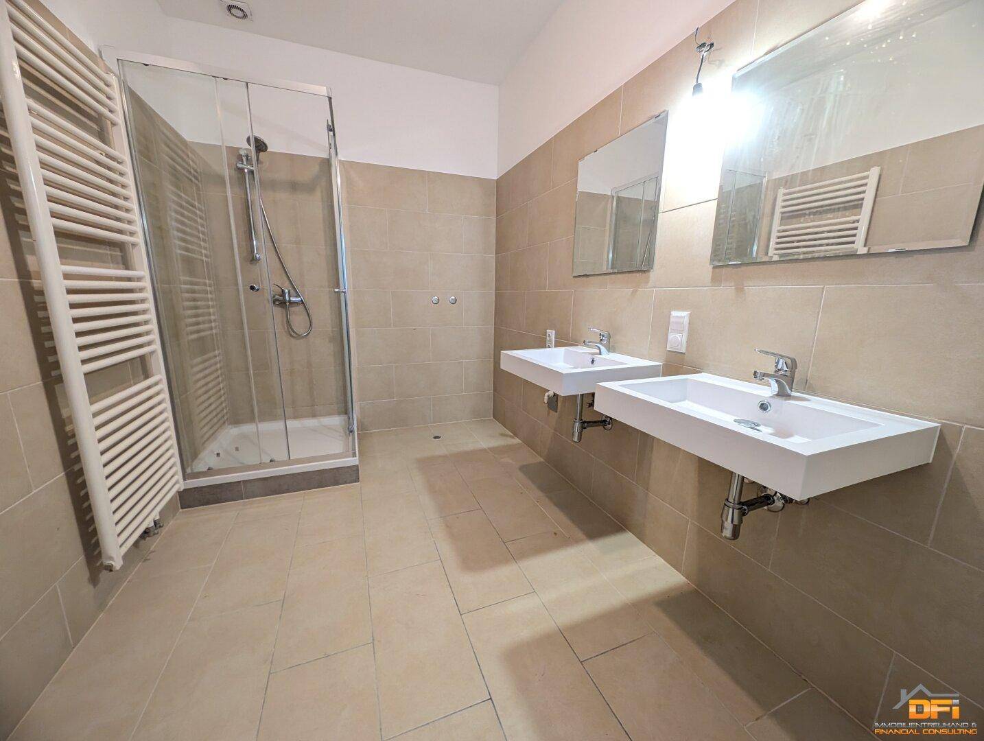 Modernes Badezimmer mit zwei Waschbecken, großer Duschkabine und beigefarbenen Wandfliesen.